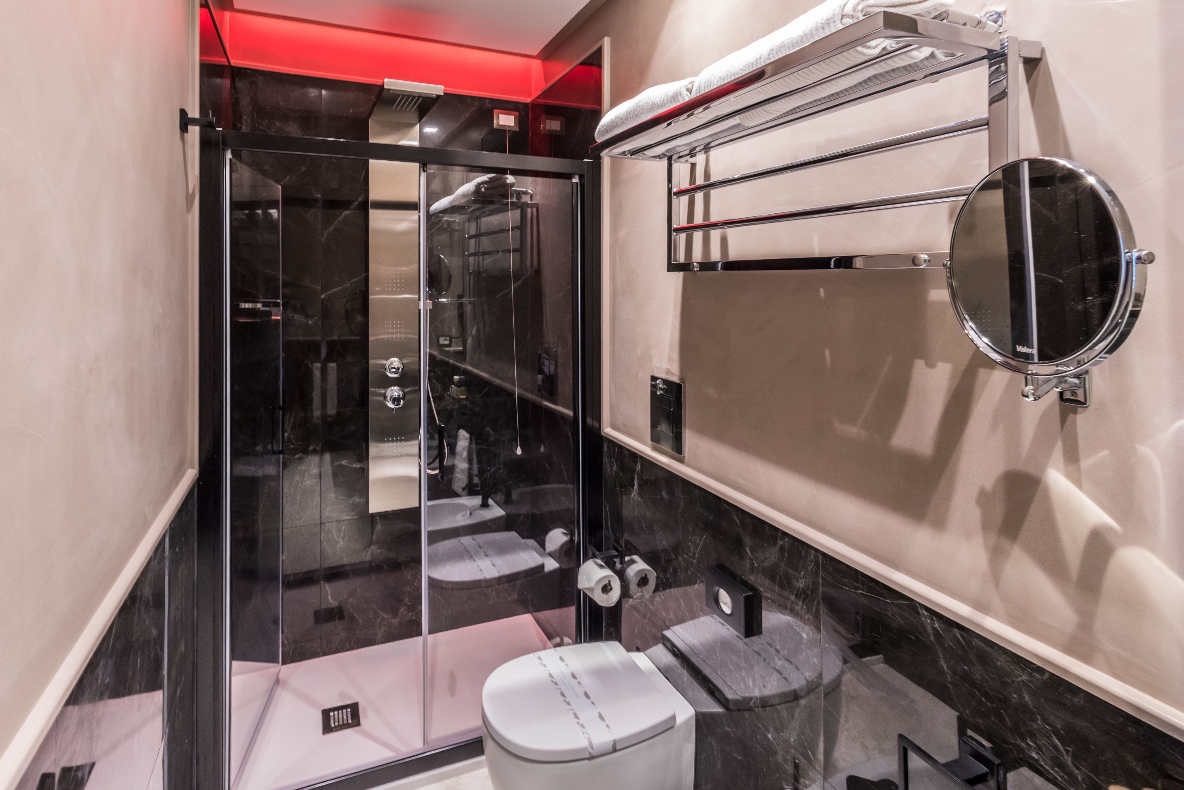 A modern bathroom with a glass shower enclosure, a toilet, a sink, and a towel rack.