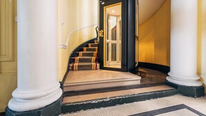 Un escalier avec un palier recouvert de moquette et une porte donnant sur une pièce.