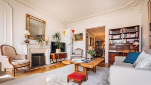 Un salon spacieux doté d’une cheminée, d’un grand miroir, d’une bibliothèque et d’un coin salon confortable.