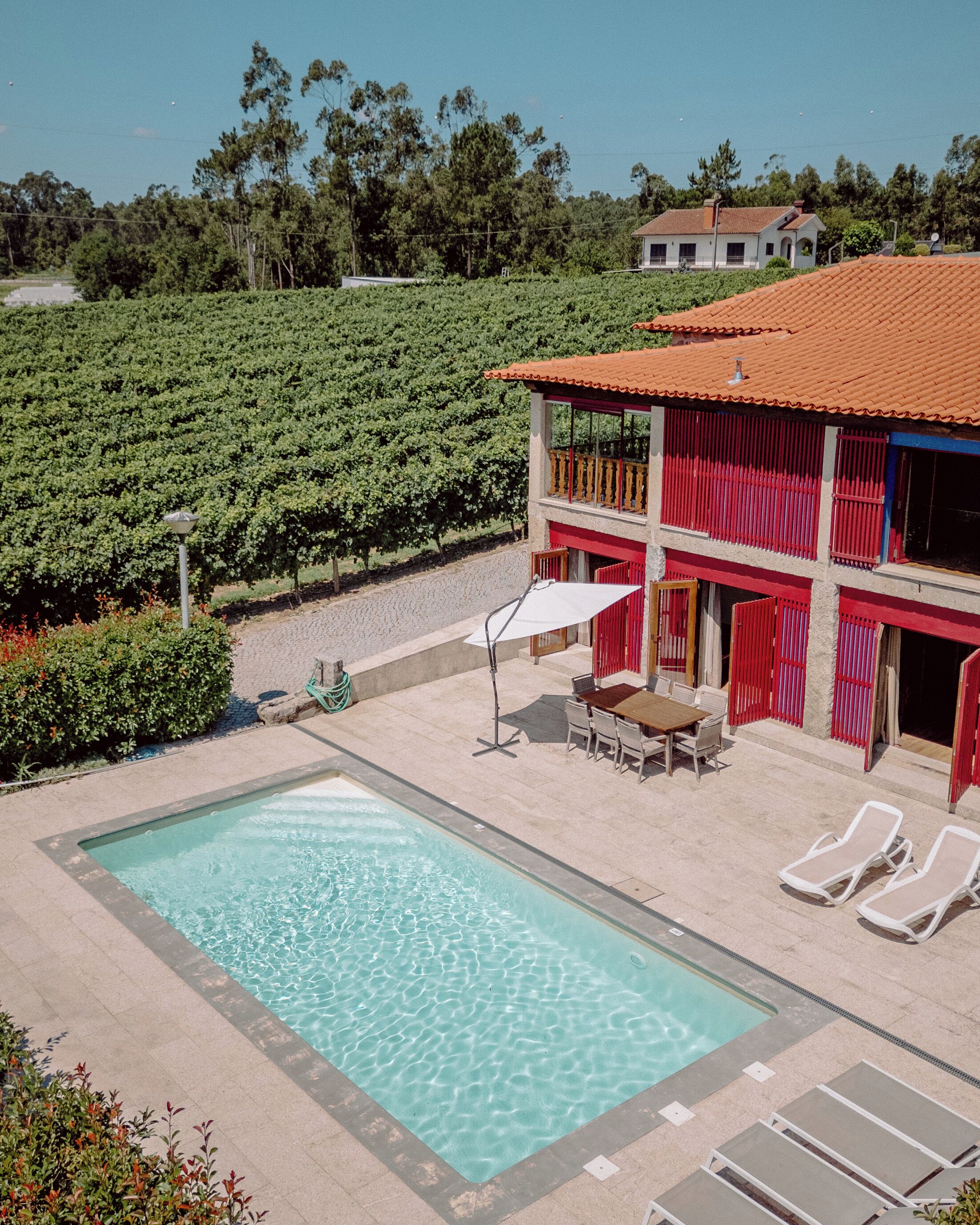 A pool area with a clear blue pool, lounge chairs, and a dining table with chairs.