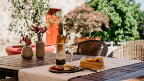Un área de comedor al aire libre con una mesa preparada para una comida, una botella de vino y una copa de vino.