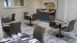 A dining area with tables and chairs, a counter with food items, and a mirror on the wall.