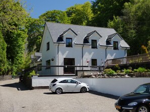 A two-story house with a sloped roof, a front porch, and a driveway. - The Brevins Guest House (Fort William)