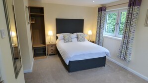 A bedroom with a bed, bedside lamps, a window with curtains, and a walk-in closet.
