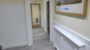 A hallway with a framed picture of mountains, a radiator, and an exit door.