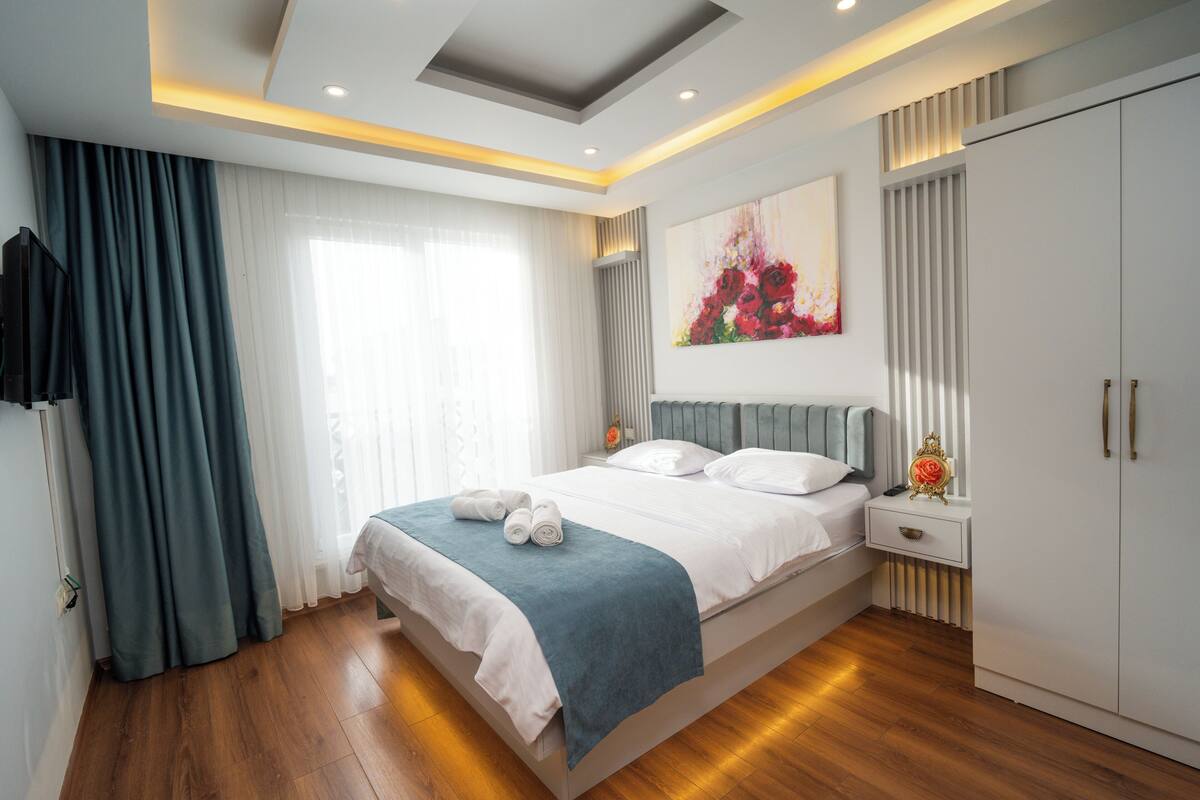 Un dormitorio moderno con una cama grande, una mesita de noche, un armario y un cuadro en la pared.