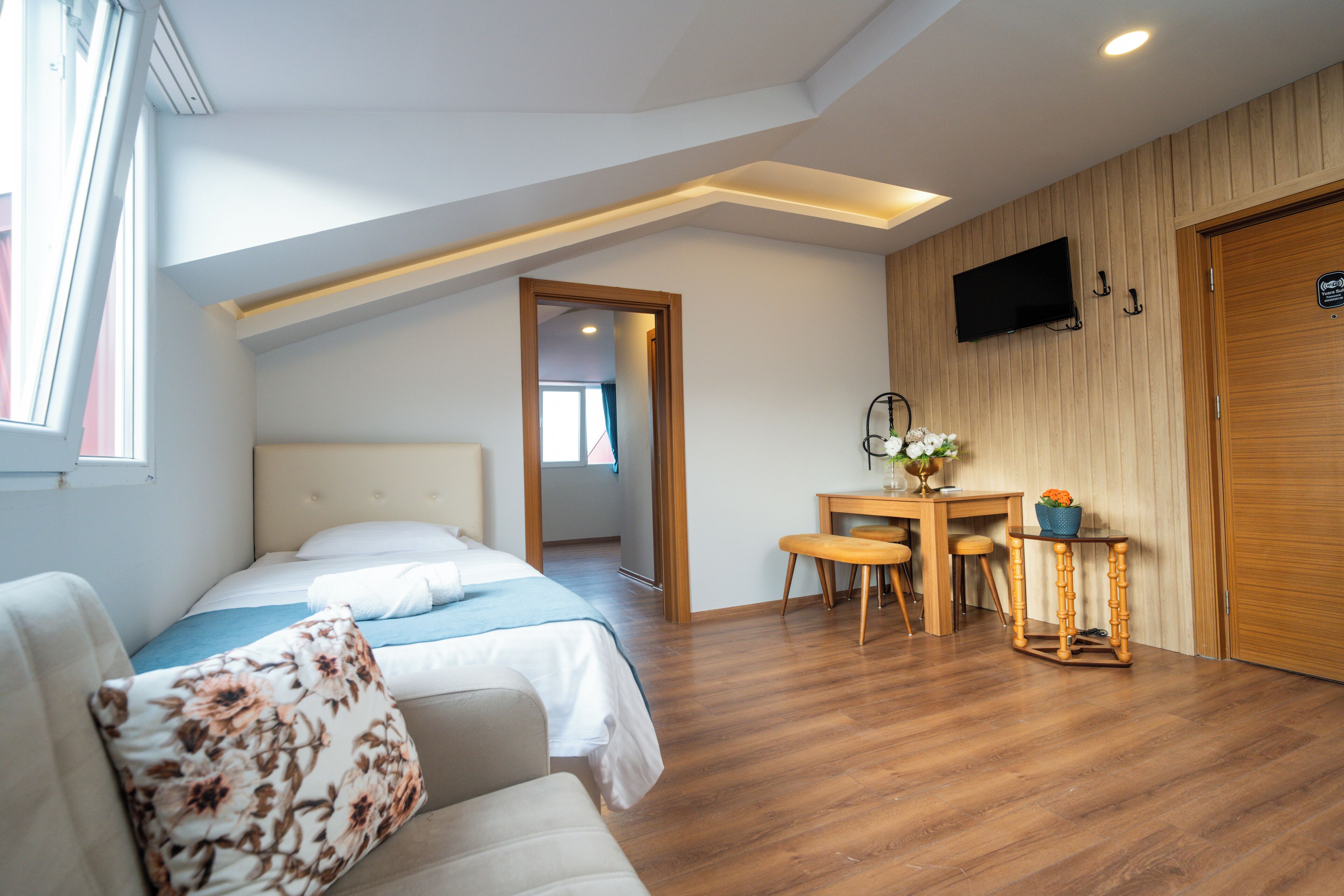 A bedroom with a bed, a desk, and a TV mounted on the wall.
