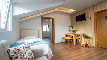 A bedroom with a bed, a desk, and a TV mounted on the wall.