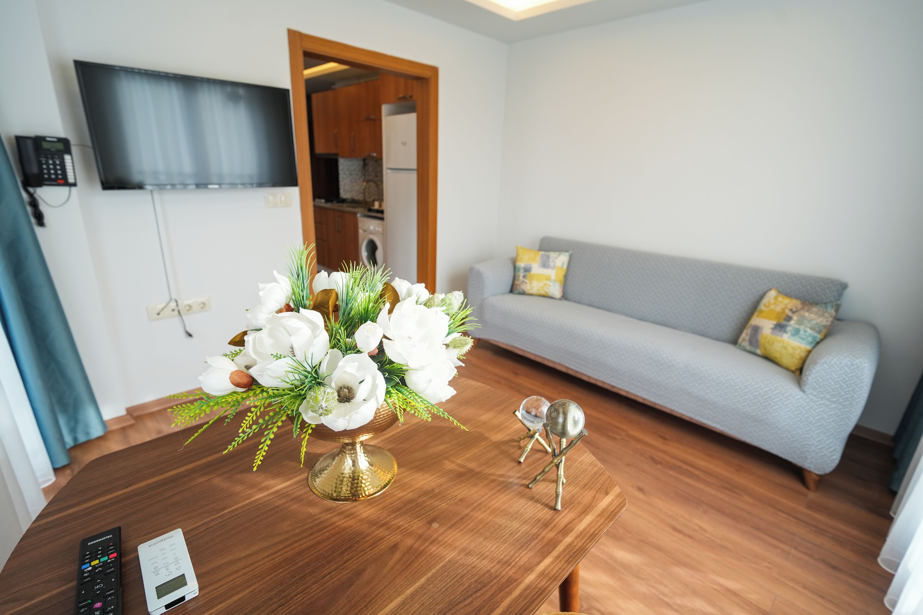 Una sala de estar moderna con una mesa de centro de madera, un sofá gris y un televisor montado en la pared.