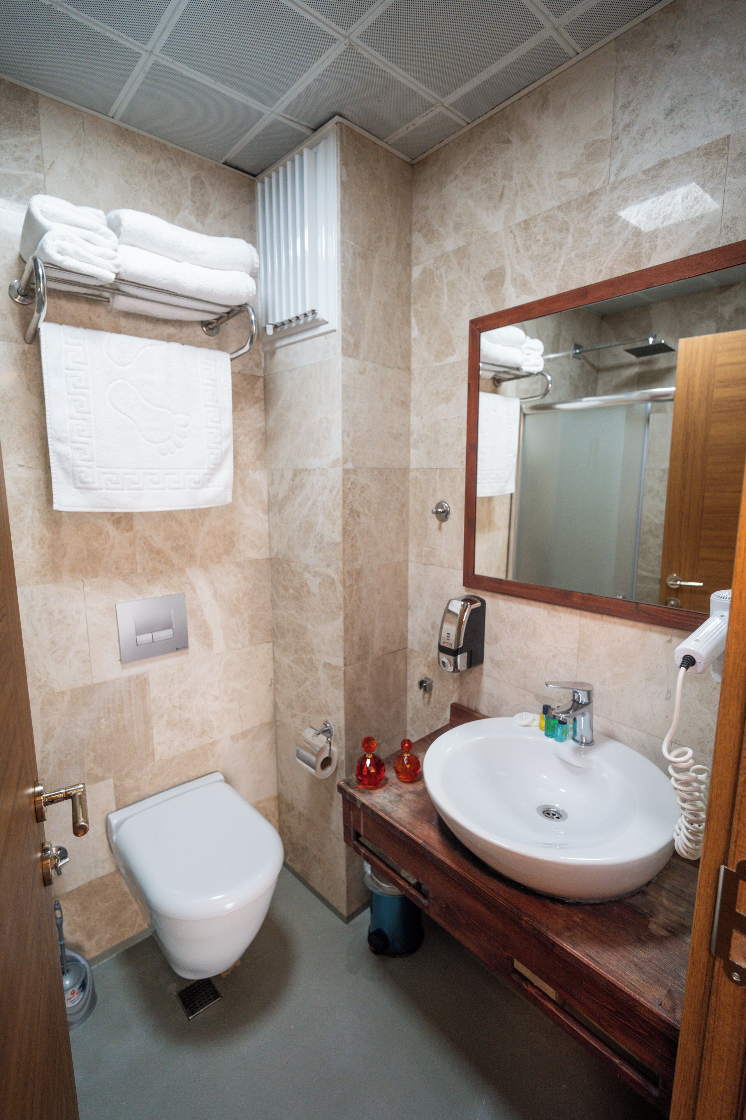 A bathroom with a toilet, sink, and mirror.