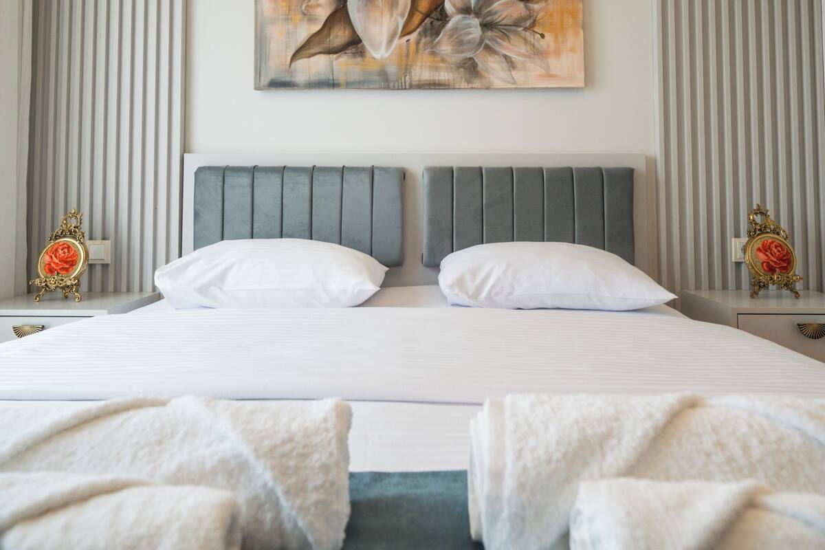 Una habitación de hotel moderna con una cama grande, un cuadro decorativo y vistas a la ciudad.