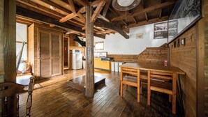 A wooden interior with a dining table, wooden beams, and a kitchen area. - Sennin Cabin Hakuba (Hakuba)