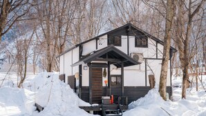 A two-story house with a wooden deck and a small porch. - Sennin Cabin Hakuba (Hakuba)