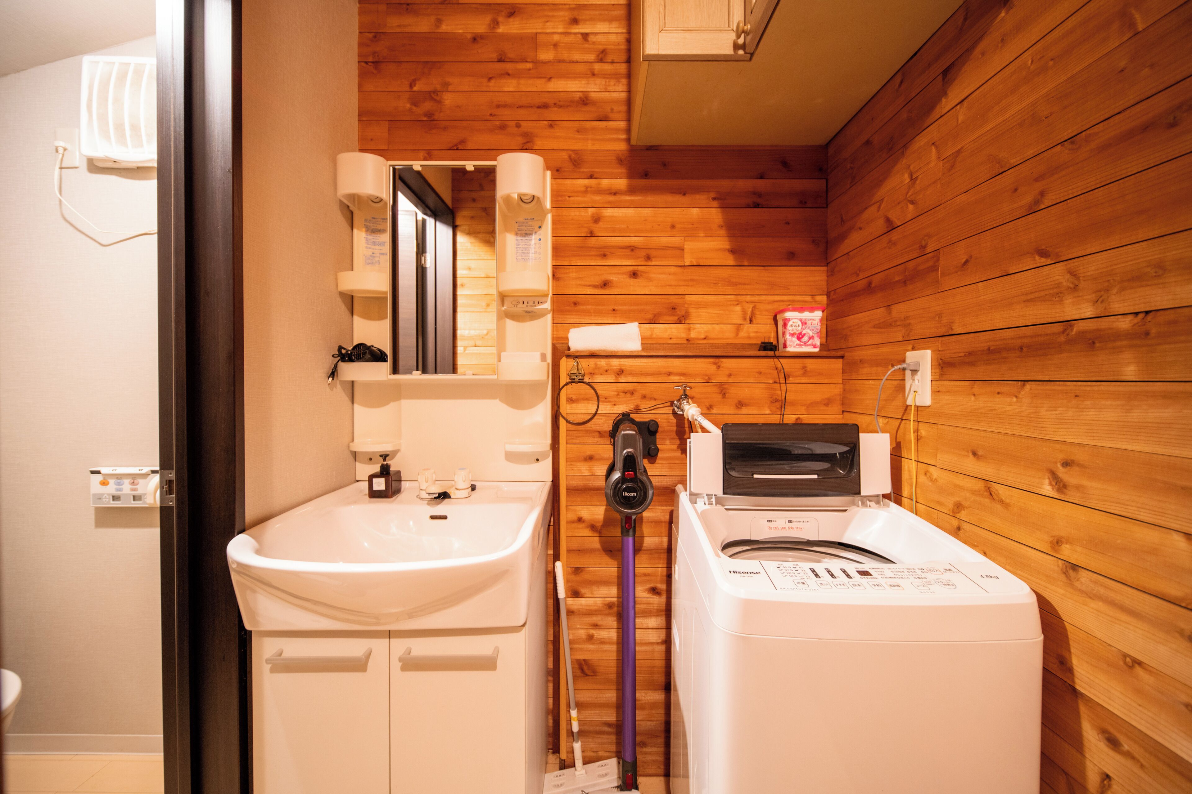 Een badkamer met een wastafel, een spiegel, een handdoekhouder en een wasmachine.