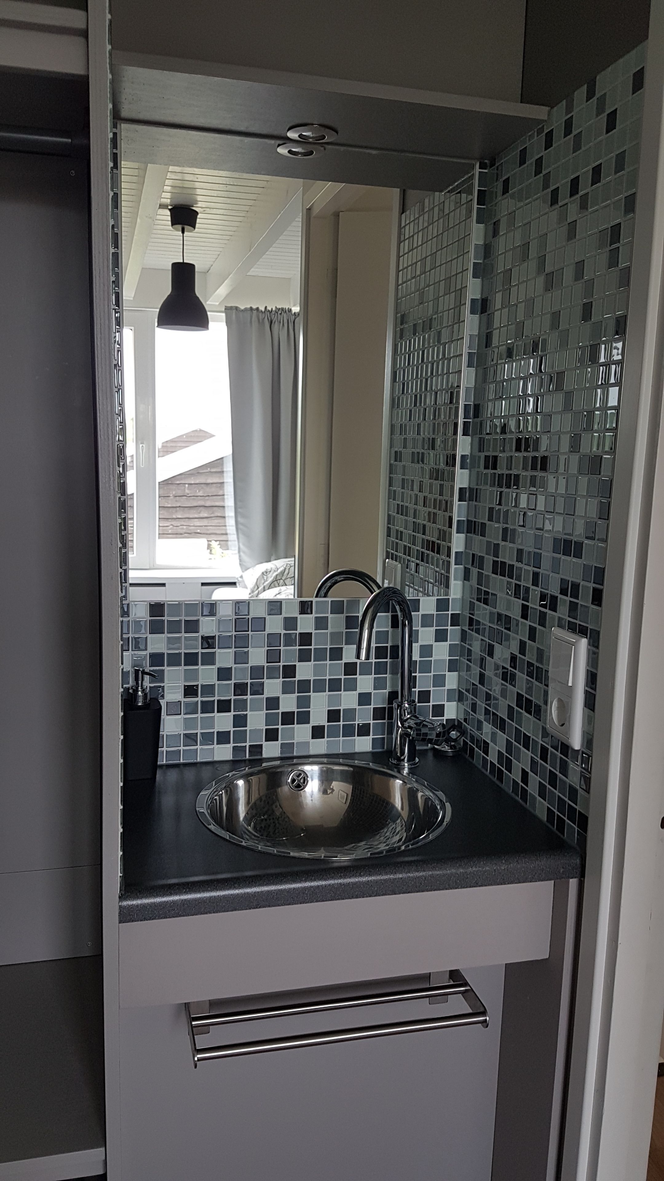 A modern bathroom with a sink, mirror, and tiled backsplash.
