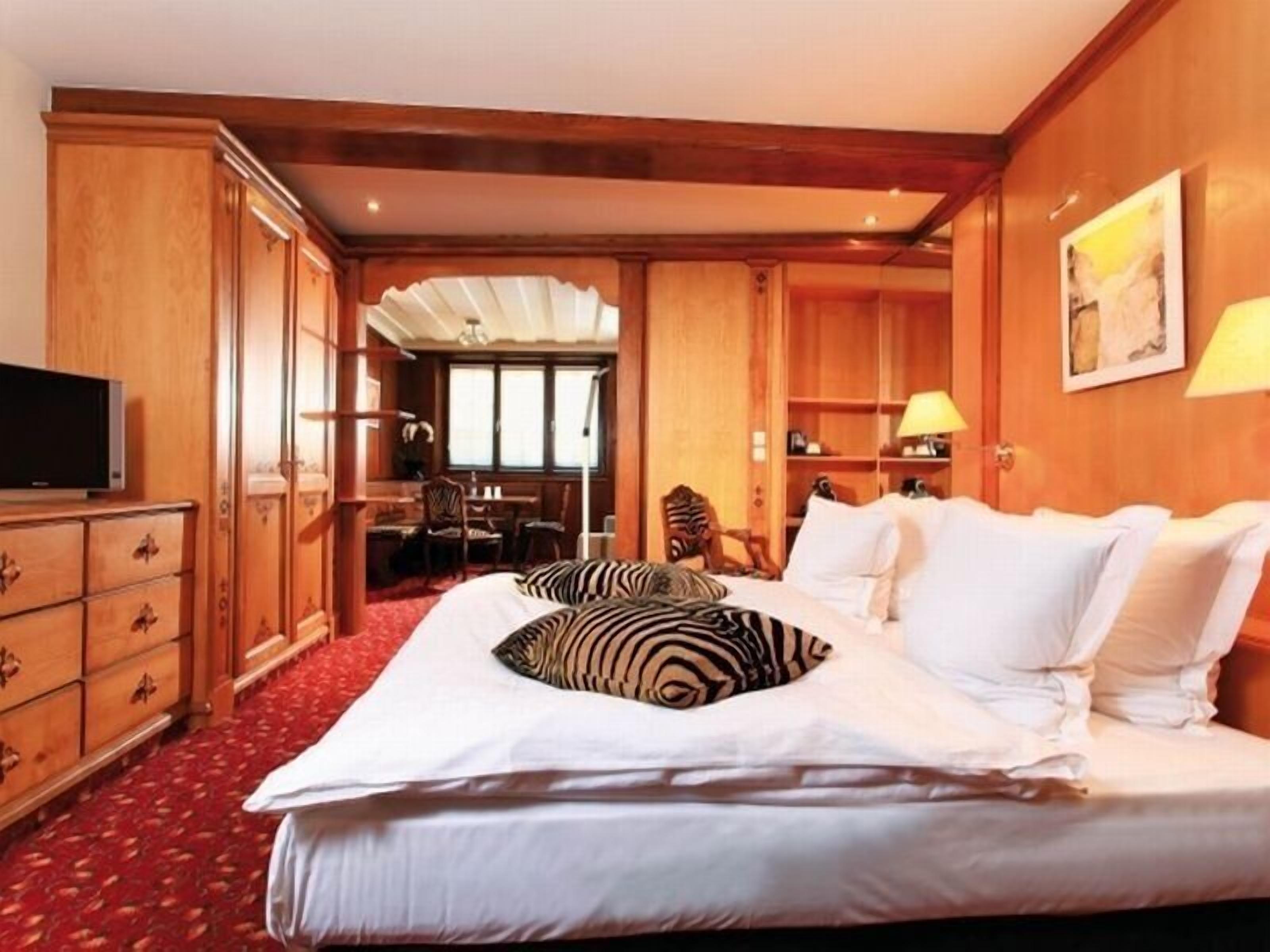 Ein Hotelzimmer mit einem großen Bett, Holzmöbeln, einem Schreibtisch und einem Fernseher.