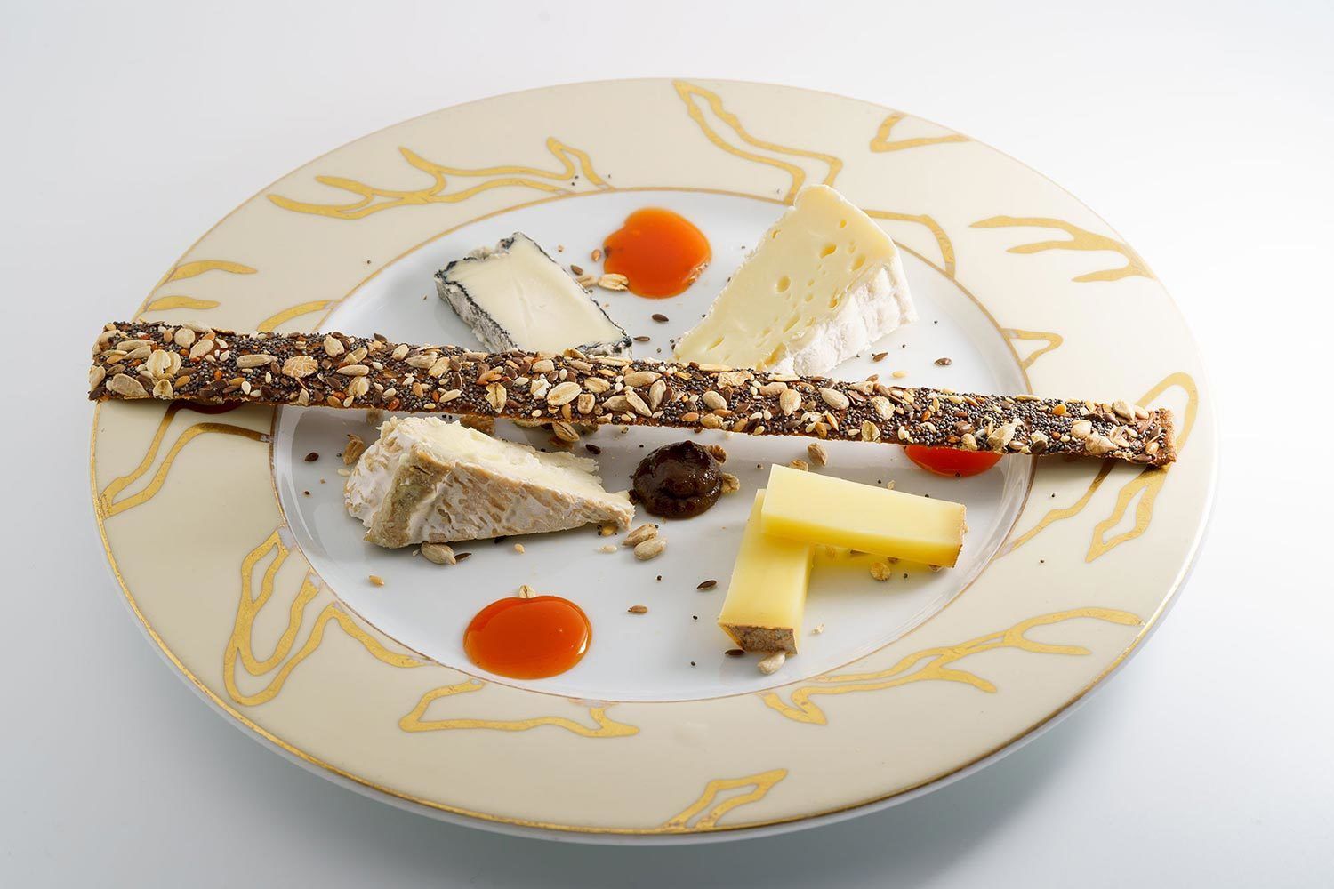 Une assiette contenant divers fromages, des noix et un morceau de chocolat.