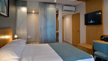 Una habitación de hotel con cama, escritorio, silla, televisor y baño.