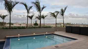 Una piscina al aire libre, sombrillas, sillones reclinables de piscina