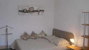 A bedroom with a bed, pillows, a bedside table with a lamp, a wall-mounted artwork, and a floor lamp. - ANNECY COQUET T2 FURNITURE, NEAR LAKE, OLD TOWN, 2 BIKES (Annecy)