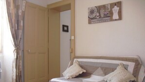 A bedroom with a bed, a door, and a wall with a clock and a mannequin. - ANNECY COQUET T2 FURNITURE, NEAR LAKE, OLD TOWN, 2 BIKES (Annecy)