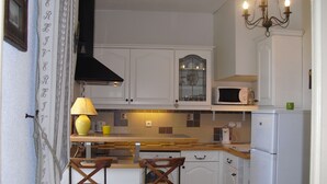 A compact kitchen with white cabinets, a microwave, a refrigerator, and two wooden chairs. - ANNECY COQUET T2 FURNITURE, NEAR LAKE, OLD TOWN, 2 BIKES (Annecy)