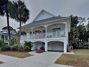 A two-story building with a balcony, a covered porch, and a garage.