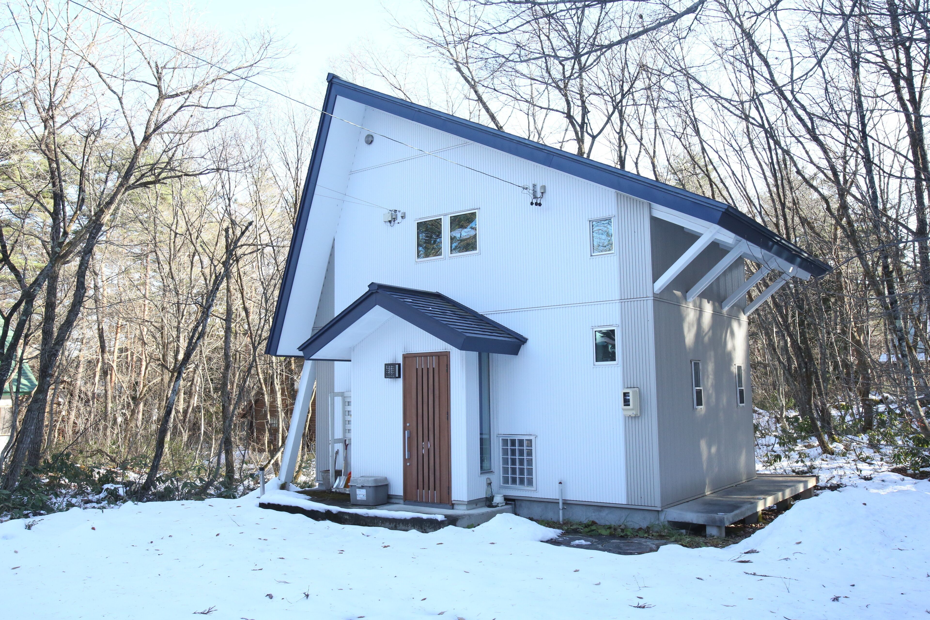 A two-story house with a sloped roof, a front porch, and a small front yard.