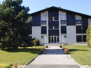 A two-story building with a central entrance, surrounded by a well-maintained lawn and potted plants.