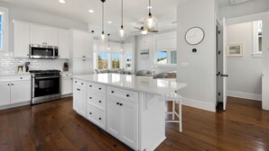 Une cuisine moderne avec des meubles blancs, des appareils en acier inoxydable et un grand îlot central.