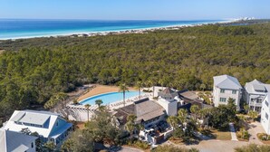 Vue aérienne d’un complexe hôtelier doté d’une piscine, d’une plage et d’une forêt dense.