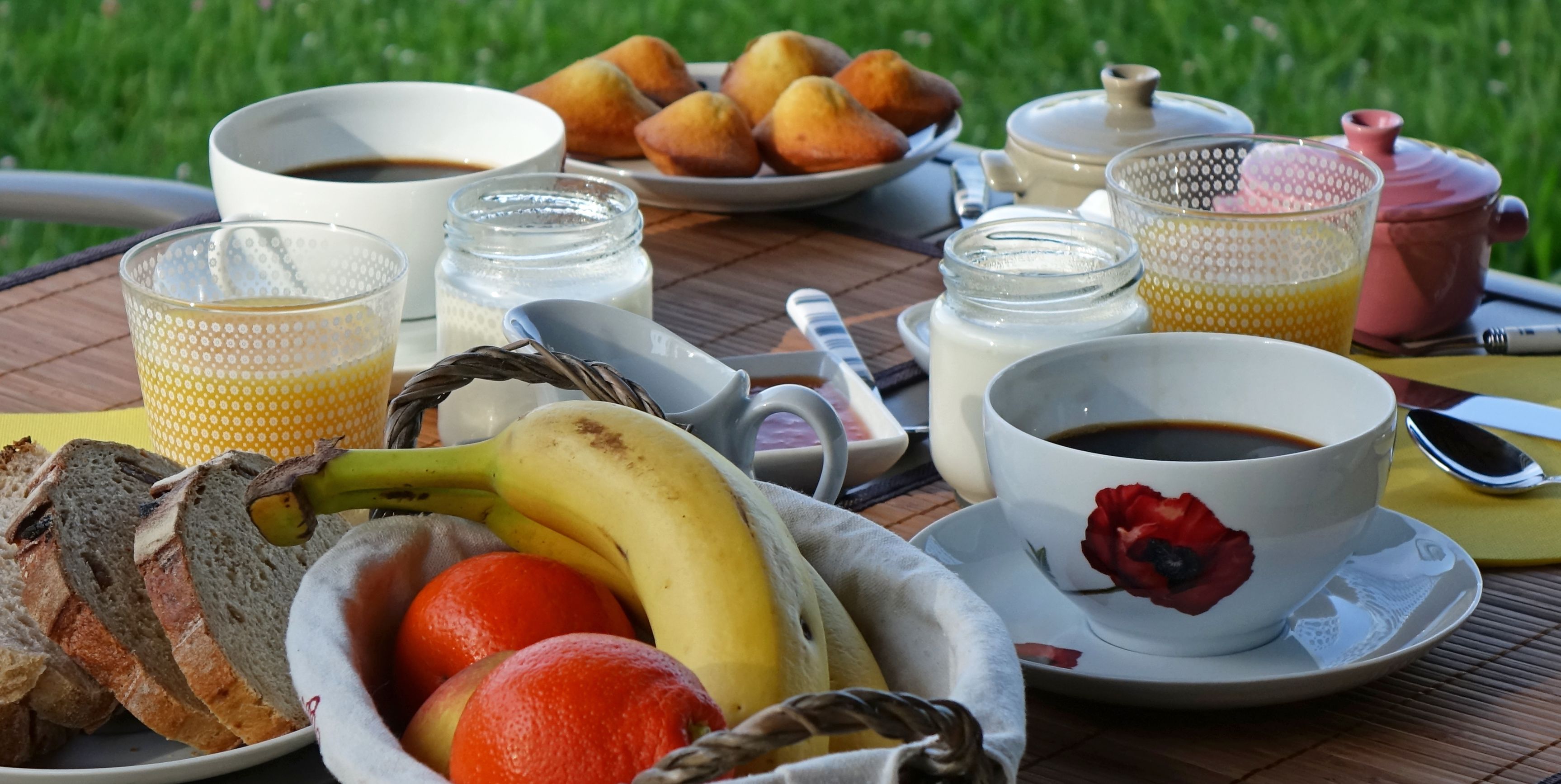 A breakfast table with bread, fruits, coffee, and pastries.
