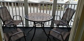 Ein Balkon mit einem runden Tisch und vier Stühlen.
