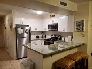 A modern kitchen with white cabinets, stainless steel appliances, a granite countertop, and a 'Relax' sign on the wall.