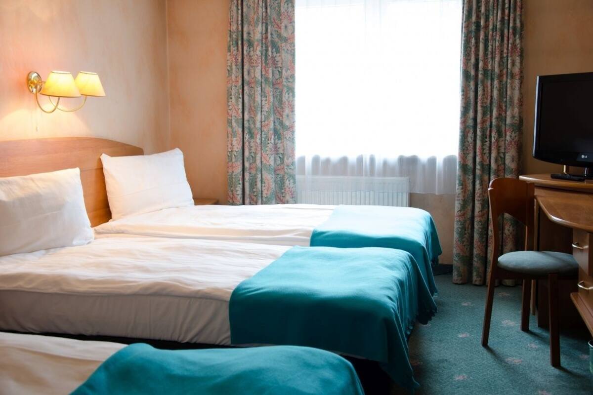 Hotellihuone, jossa on kaksi sänkyä, työpöytä, tuoli ja televisio.