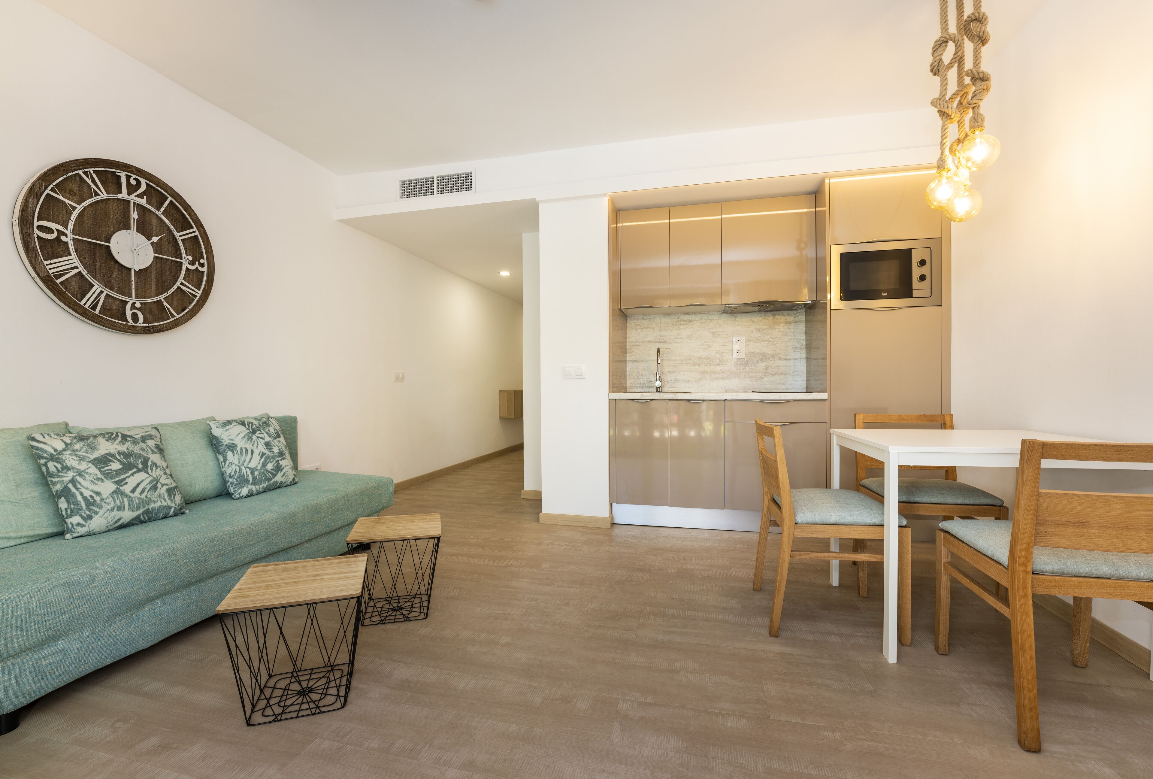 A modern living room with a sofa, coffee table, and dining area with chairs and a table.