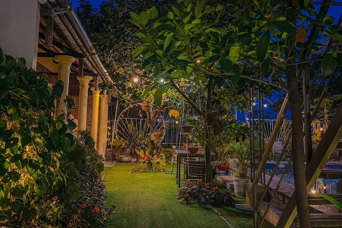 Un jardin bien entretenu, agrémenté d’un chemin, de plantes en pot et d’un escalier menant à un niveau supérieur.