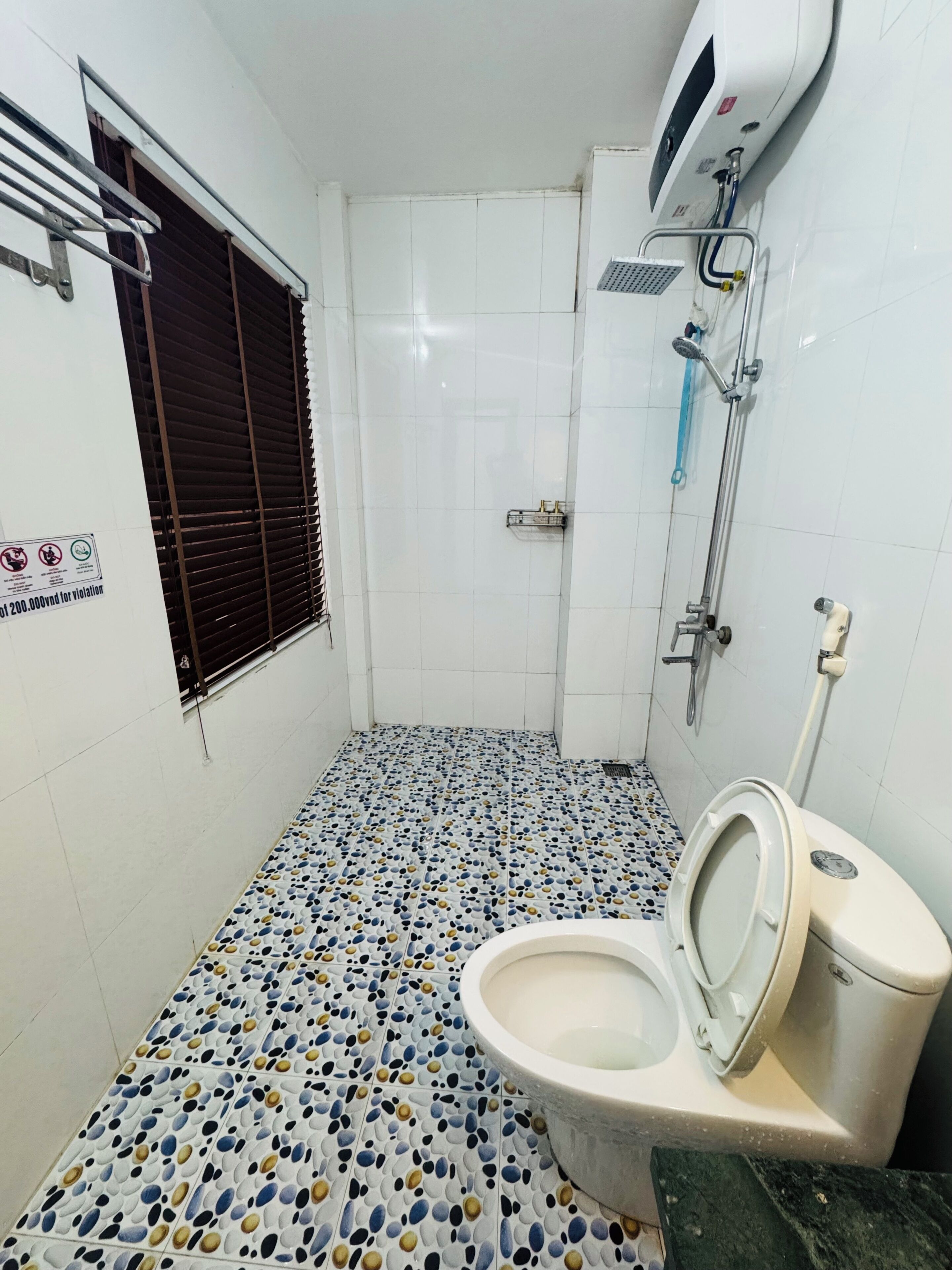 Une salle de bain avec des toilettes, une douche et un sol carrelé.