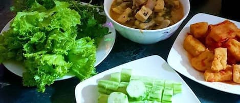 A table with various dishes including fried items, a bowl of soup, and fresh vegetables.