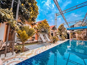 A swimming pool with tiled edges, surrounded by potted plants and a metal staircase leading to a building. - Tam Coc Sunrise Homestay (Nam Hoa Lu)