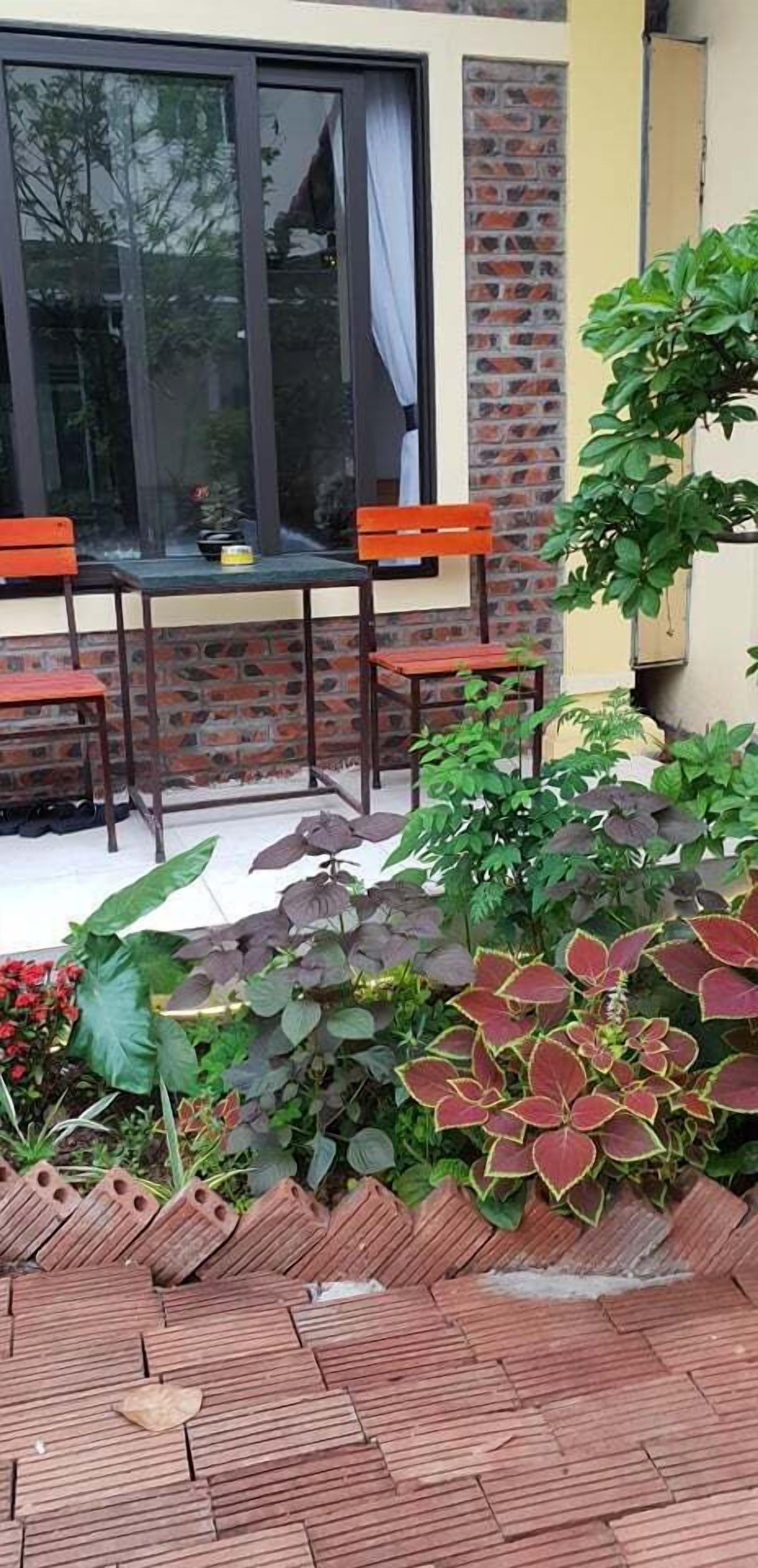 A patio area with a table and chairs, surrounded by potted plants and a brick wall.