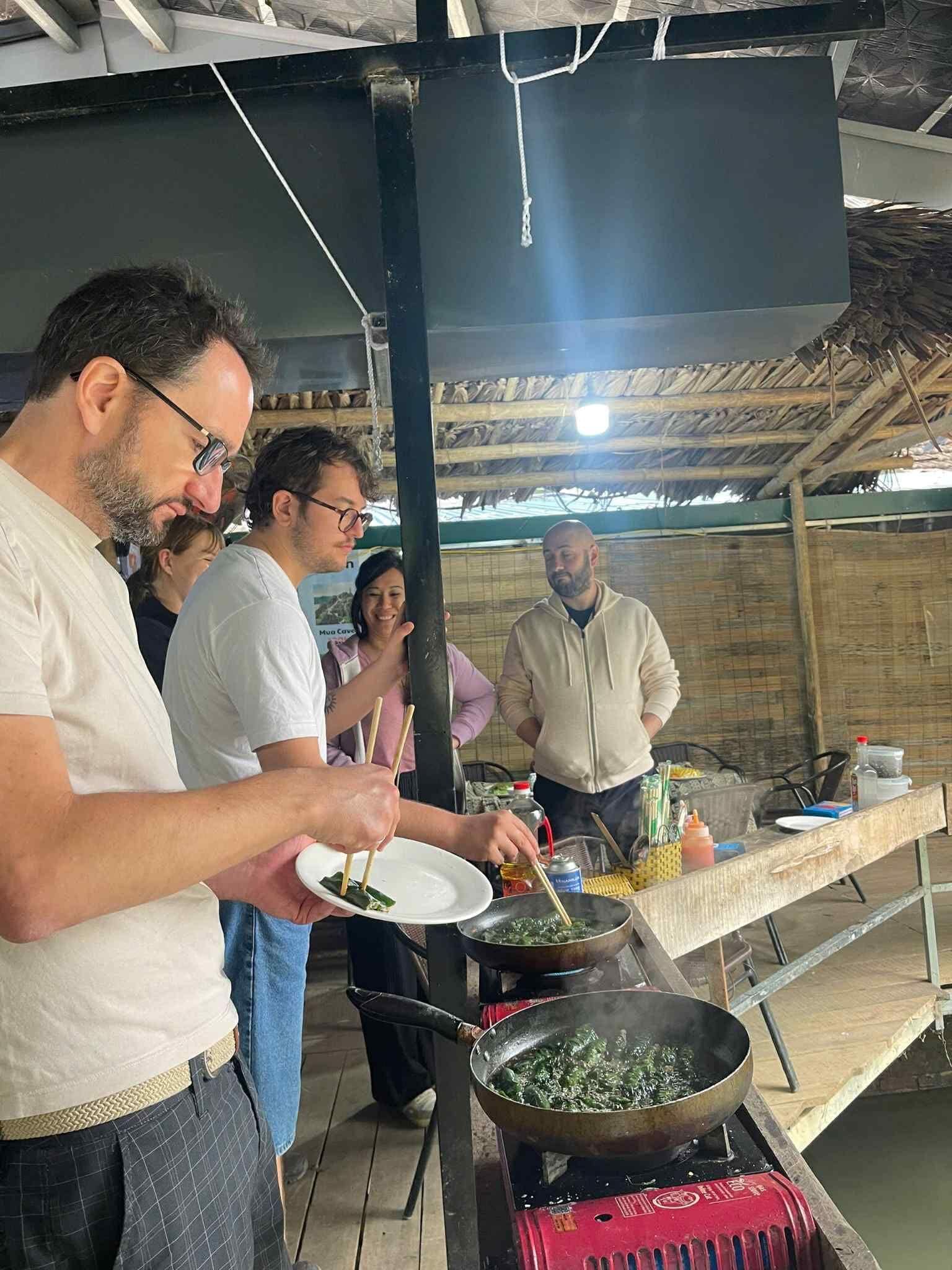 A group of people cooking outdoors with a large pot on a portable stove.