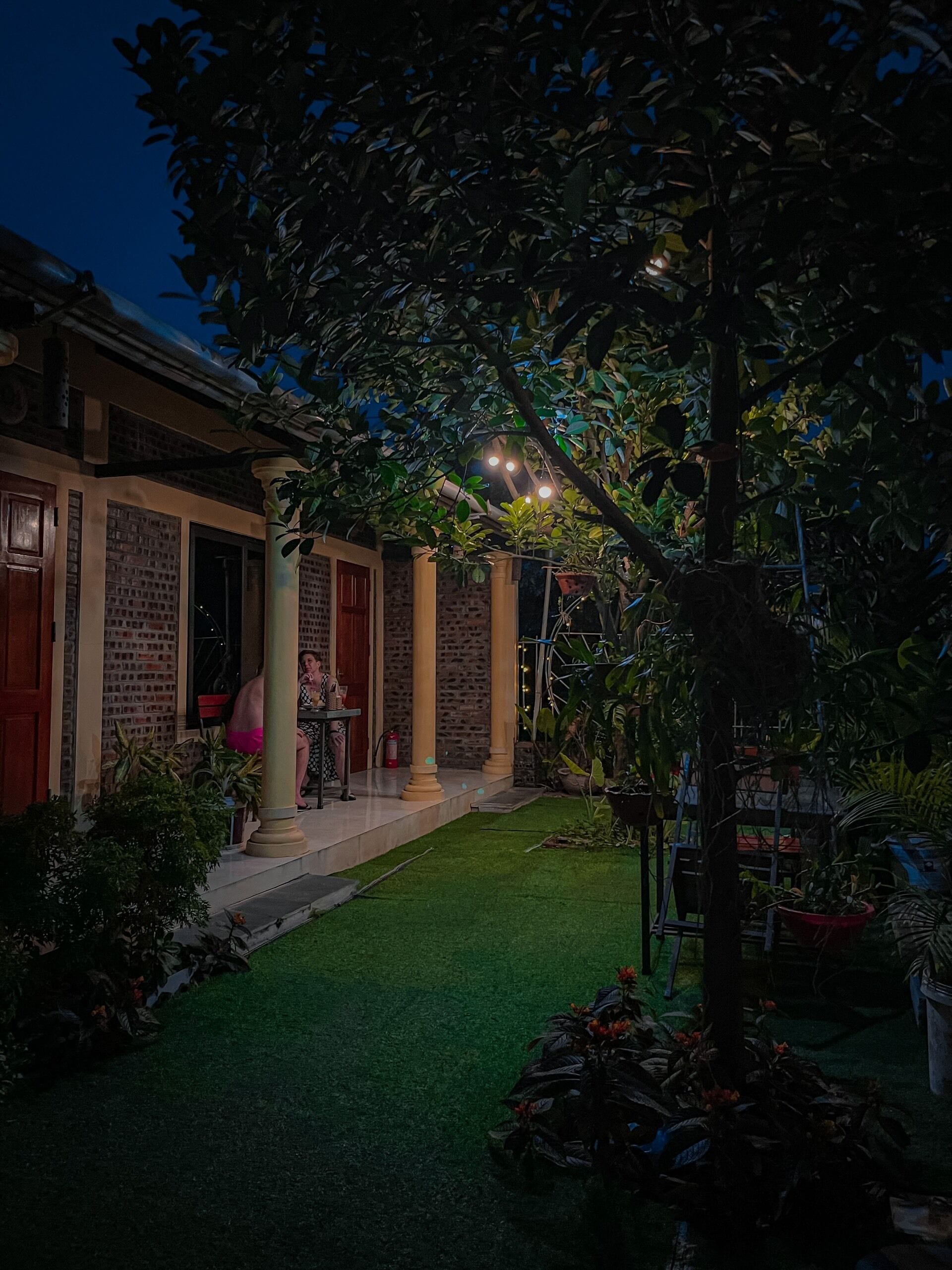 A courtyard with a brick building, a covered seating area, and a well-maintained lawn.