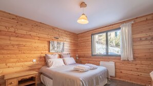 Ein Schlafzimmer einer Holzhütte mit Bett, Nachttisch, Fenster und Heizkörper.
