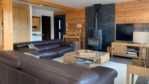 Ein modernes Wohnzimmer mit Ledersofa, Kamin, Fernseher und Holzwänden.