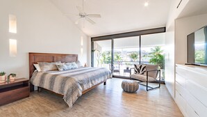 Une chambre dotée d’un grand lit, d’un ventilateur de plafond, d’un balcon avec vue et d’un téléviseur fixé au mur.