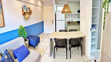 Um espaço compacto com área de refeições, cozinha compacta e sala de estar com sofá e cadeiras.