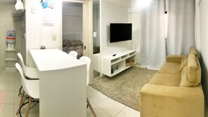 A compact living space with a kitchenette, a dining area, a sofa, and a TV. - Vacanze - Gales da Pajuçara (Maceió)
