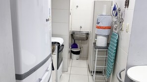 Un baño estrecho con inodoro, lavamanos y un pequeño cubo de basura.
