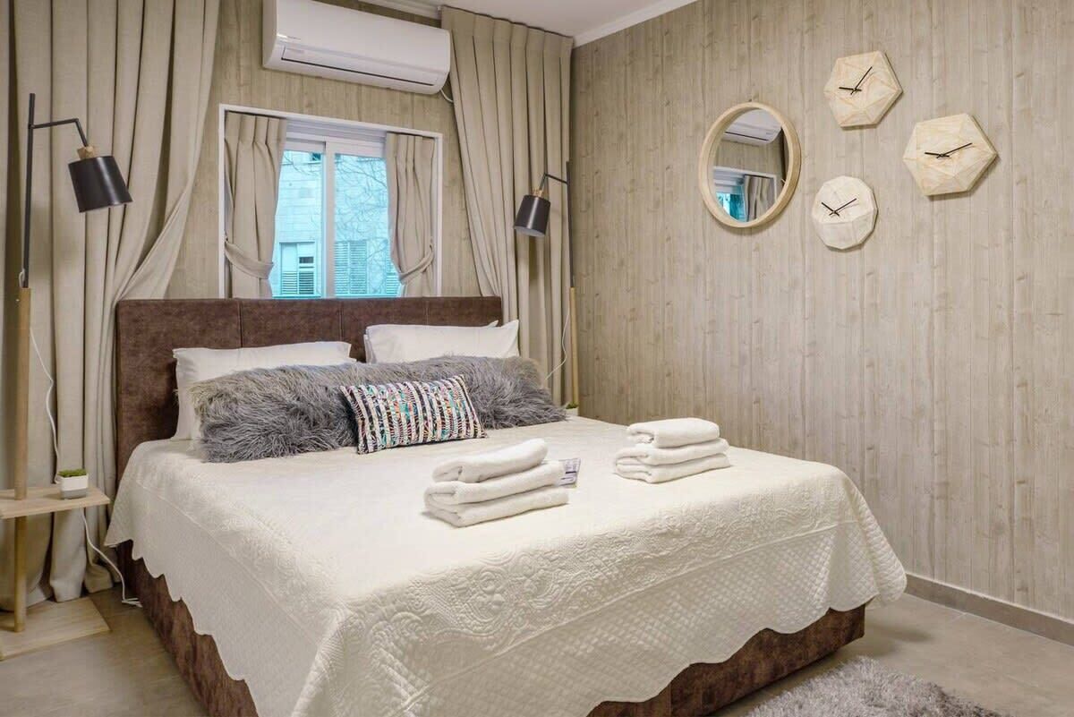 Quarto com uma cama grande, duas luminárias de cabeceira, uma janela com cortinas e um relógio de parede.